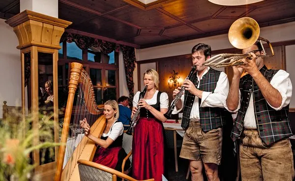 Vier Musizierende in Tracht mit Harfe, Klarinetten und Posaune